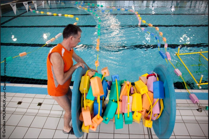 Tenue de rigueur obligatoire.<br>J’ai 2 sachets en plastique bleu qui  me transforme en cosmonaute des bassins… (petits sachets hygiéniques pour éviter de rentrer des impuretés à l’intérieur des lieux). Un reportage dédié à ce lieu et aux multiples activités qui s’y rapportent.<br><br>Il y a des missions photographiques comme celle-ci qui vous marquent, vous embarquent et ne vous lâchent plus. Je suis en totale immersion dans ces lieux, et petit-à-petit, je me fonds dans la foule. Pour mon plus grand plaisir, les regards oublient mon boitier, ma présence.<br><br>Je découvre alors des univers différents… qui se côtoient. Aquaphobes, sportifs, scolaires, adeptes du fitness et de la sculpture du corps, handicapés moteur, handicapés psychiques, accompagnateurs, familles, enfants, plongeurs…<br>J’ai pris le temps. De m’arrêter, de comprendre, de discuter… afin que les images soient justes. « Lorsque l’on est dans l’eau, on ne voit plus la différence entre un valide et un handicapé. On enlève même le fauteuil en bord de bassin le temps d’une liberté retrouvée… »<br><br>Les rencontres sont belles.<br>Joyeuses, émouvantes, pleines d’eau et d’éclaboussures, de pudeur et de rire.Merci pour l’accueil, pour cette mission photographique, qui me rappelle pourquoi j’aime ce métier.